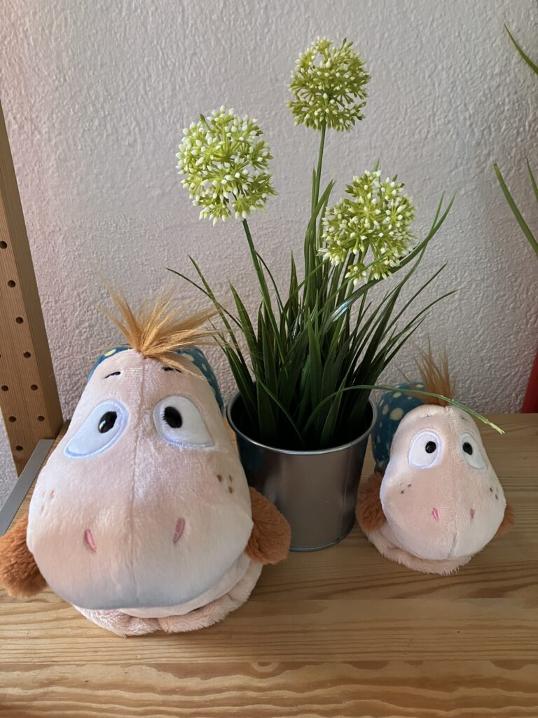 Zwei kleine Schnecken-Figuren neben einer Pflanze – ruhiger, geschützter Moment als Symbol für Alltag mit Hör-Herausforderungen