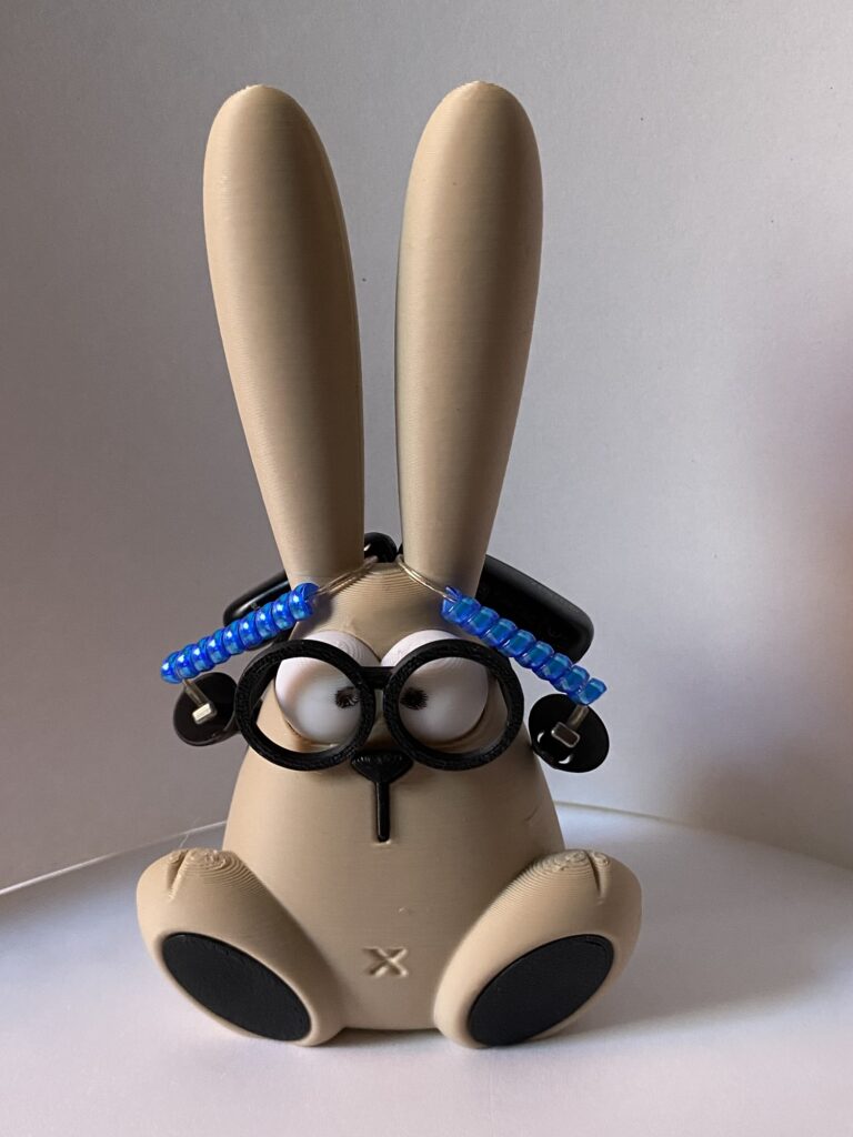 Der Hüter der Hörfreunde Kleiner Hase mit Brille trägt Hörgeräte über den Ohren und sitzt ruhig vor einem schlichten Hintergrund.
