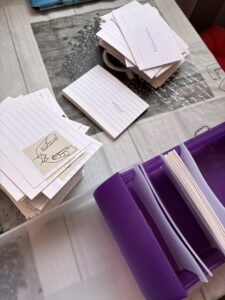 Karteikarten mit Gebärdenzeichnungen liegen auf einem Tisch neben einer geöffneten Karteikartenbox.